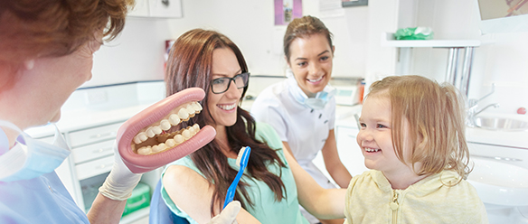 A dentist showing a mouthguard to little girl