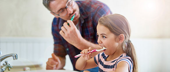 A Girl brushing her teeth with her father