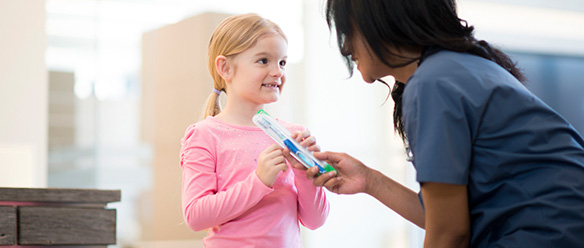 A little girl is getting a new tooth brush from a dentist