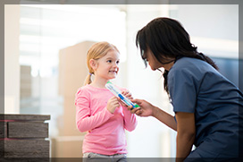 A little girl is getting a new tooth brush from a dentist