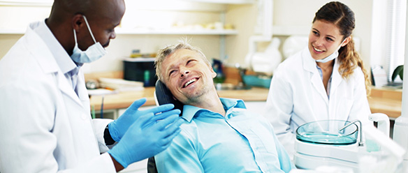 Friendly dentist and his nurse, talking to a male patient