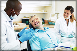 Friendly dentist and his nurse, talking to a male patient